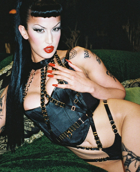 glamourous fetish pinup model in corset and black and gold harness bodysuit